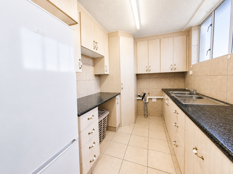 Functional laundry room featuring light wood cabinetry, dark granite countertops, stainless steel sink, and tiled flooring with dedicated plumbing connections.