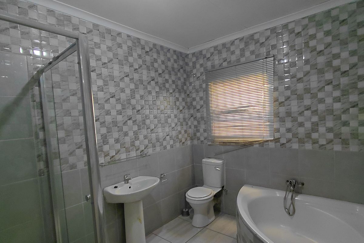 A functional bathroom featuring a corner bathtub, separate shower enclosure, pedestal basin, and toilet with tiled finishes throughout.
