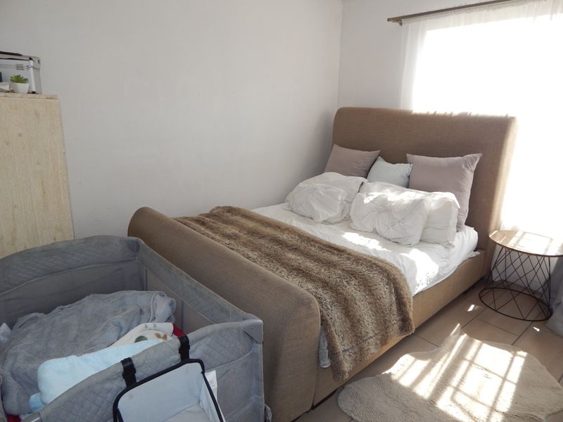 A bedroom featuring tiled flooring and natural light from a window with a curtain rod.