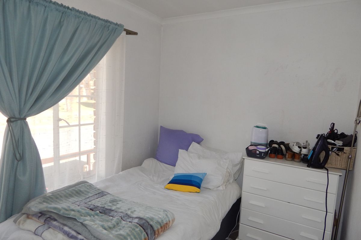A compact bedroom featuring a window with curtain rod and coving, providing a functional space for rest.