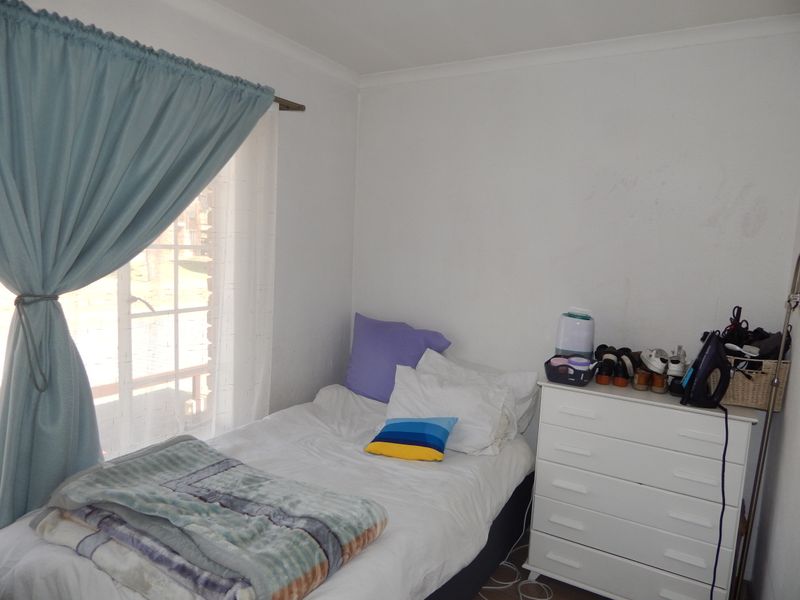 A compact bedroom featuring a window with curtain rod and coving, providing a functional space for rest.