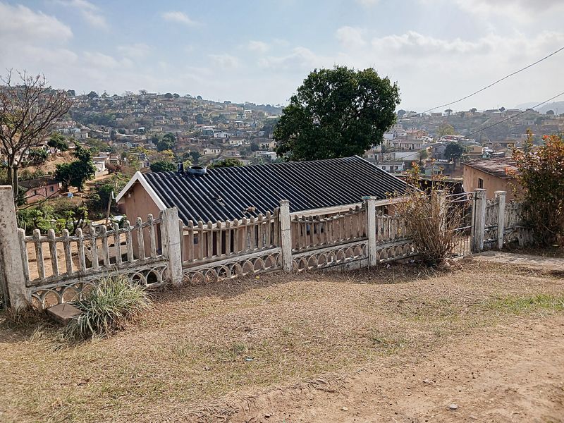 View of the rear exterior of the house featuring a corrugated metal roof and a precast concrete boundary fence overlooking the surrounding neighborhood.