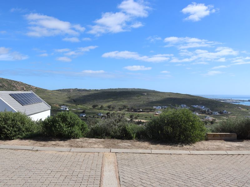 Elevated view overlooking the surrounding landscape and coastal area, featuring a nearby property with installed solar panels.