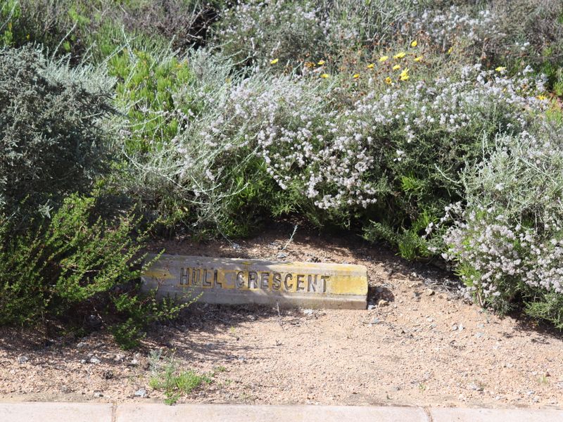 A street name sign for Hull Crescent situated in a landscaped verge area.