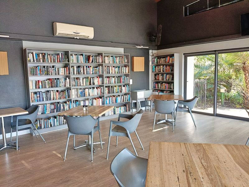 A spacious living area featuring extensive built-in bookshelves, laminate flooring, and large sliding glass doors providing natural light and garden access.