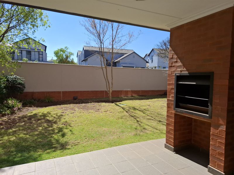 Covered patio featuring a built-in braai, tiled flooring, and direct access to a private garden area.