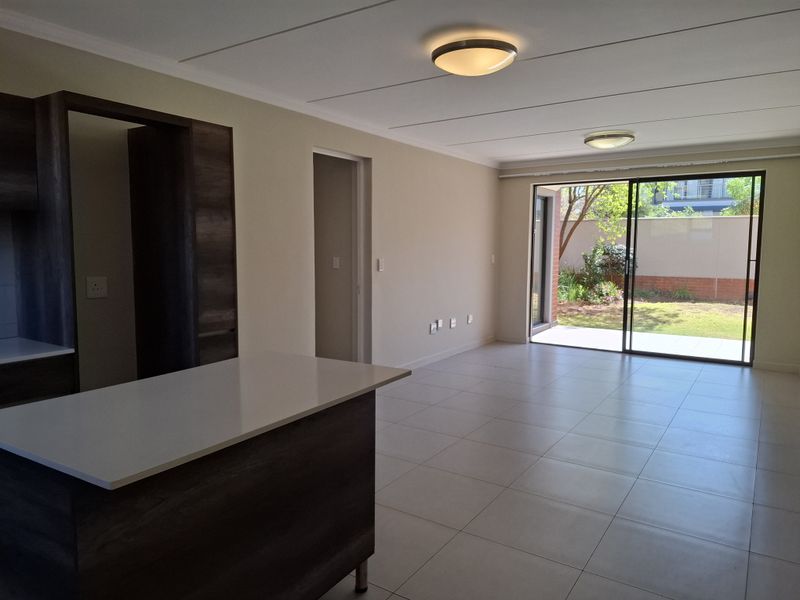 Spacious open-plan living area featuring modern tiled floors, built-in cabinetry, and large sliding doors opening to a private garden.