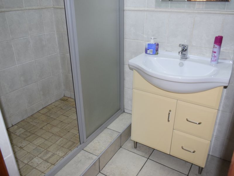A functional bathroom featuring a shower enclosure with a glass door and a vanity cabinet with a ceramic basin.