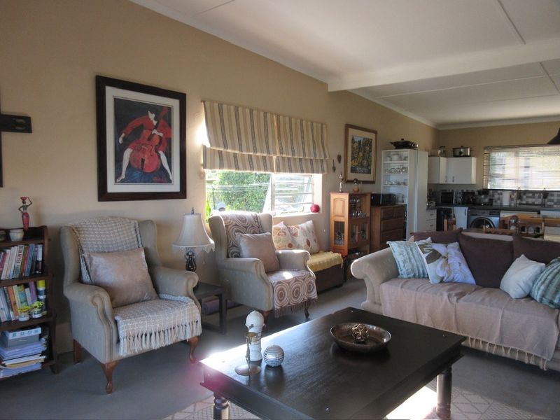 Open plan living area featuring a combined lounge space and a functional kitchen with built-in cabinetry and tiled backsplash.