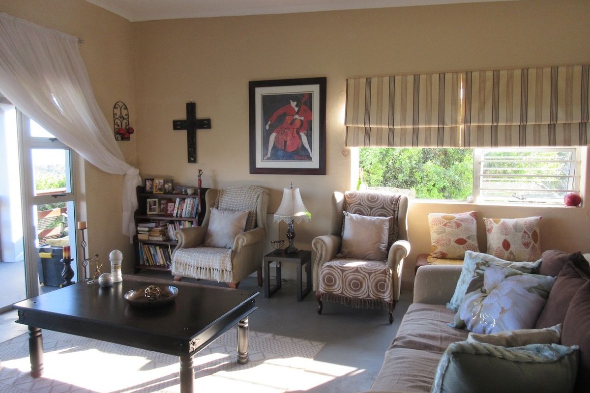 A comfortable living room featuring a sliding glass door leading to an outdoor area and large windows with fitted roman blinds.