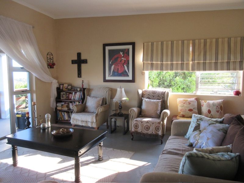 A comfortable living room featuring a sliding glass door leading to an outdoor area and large windows with fitted roman blinds.