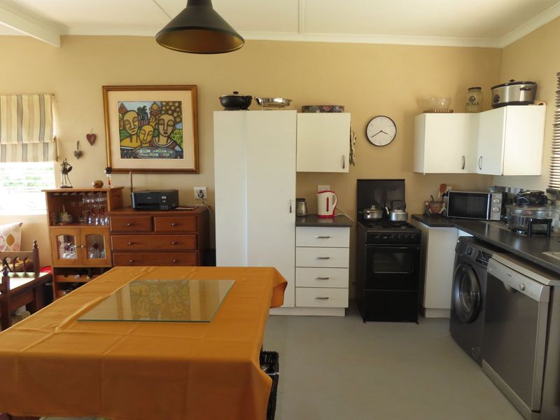 A functional kitchen featuring white cabinetry, dark countertops, a freestanding stove, and integrated laundry and dishwasher appliances.