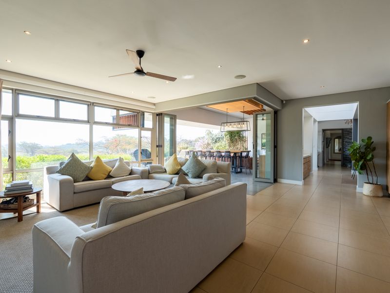 Spacious open-plan living area featuring large format floor tiles, recessed lighting, and seamless indoor-outdoor flow through bi-fold doors to the patio.