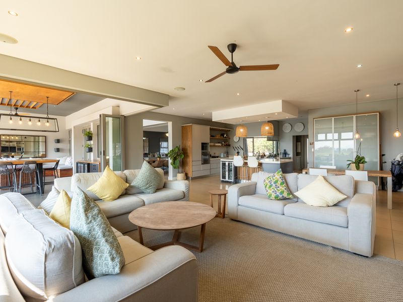 Spacious open-plan living area featuring a modern kitchen with island, integrated appliances, recessed lighting, and seamless flow to outdoor spaces via bi-fold doors.