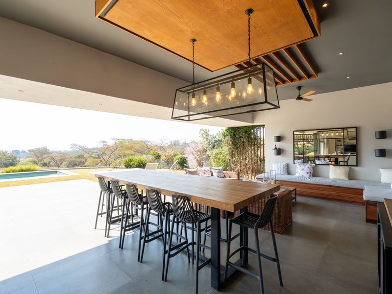 Spacious covered patio featuring a timber ceiling detail, built-in bench seating, and seamless transition to the outdoor pool area and garden.