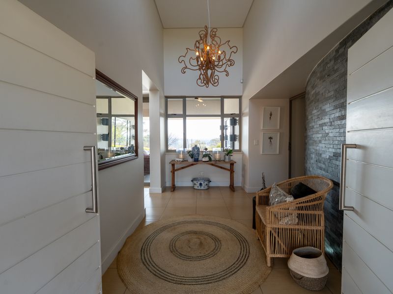 Welcoming entrance hall featuring high ceilings, a striking stone feature wall, and large windows that provide natural light and a view.