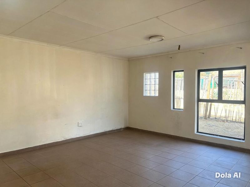 An empty living room featuring tiled flooring, aluminium window frames, and a glass block window, providing a blank canvas for interior design.