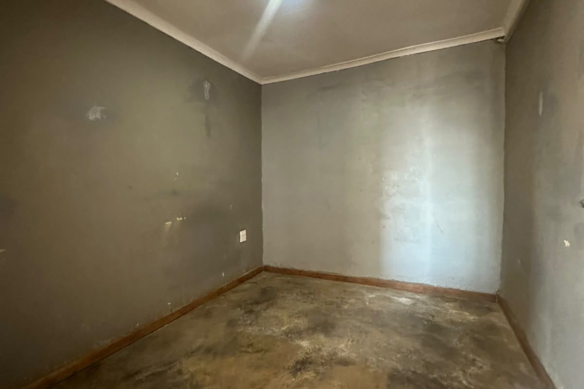 An empty bedroom featuring plain walls and flooring in need of refurbishment and cosmetic updates.