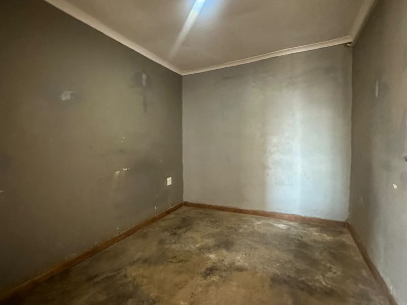 An empty bedroom featuring plain walls and flooring in need of refurbishment and cosmetic updates.