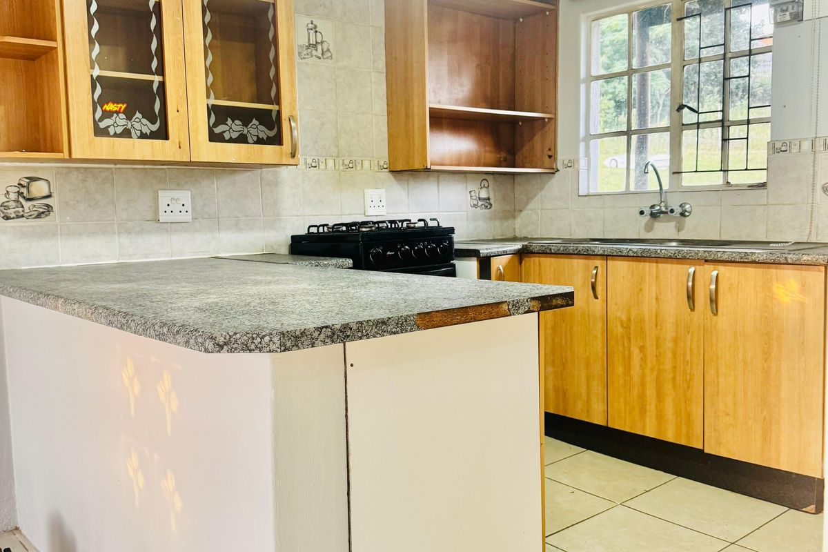 A dated kitchen featuring laminate cabinetry, a gas stove, and tiled finishes, currently in need of cosmetic updates and repairs to the cabinetry and countertops.