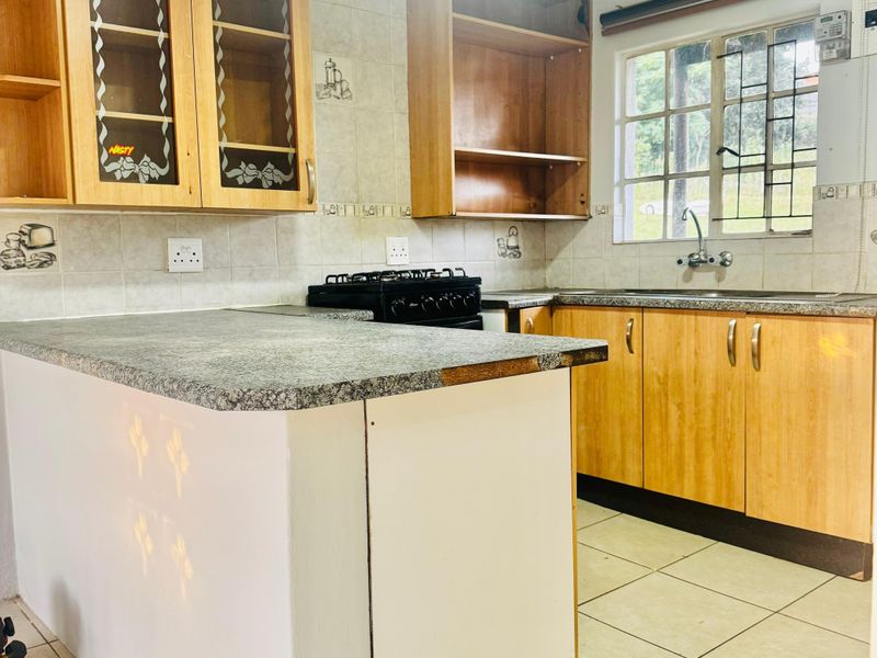 A dated kitchen featuring laminate cabinetry, a gas stove, and tiled finishes, currently in need of cosmetic updates and repairs to the cabinetry and countertops.