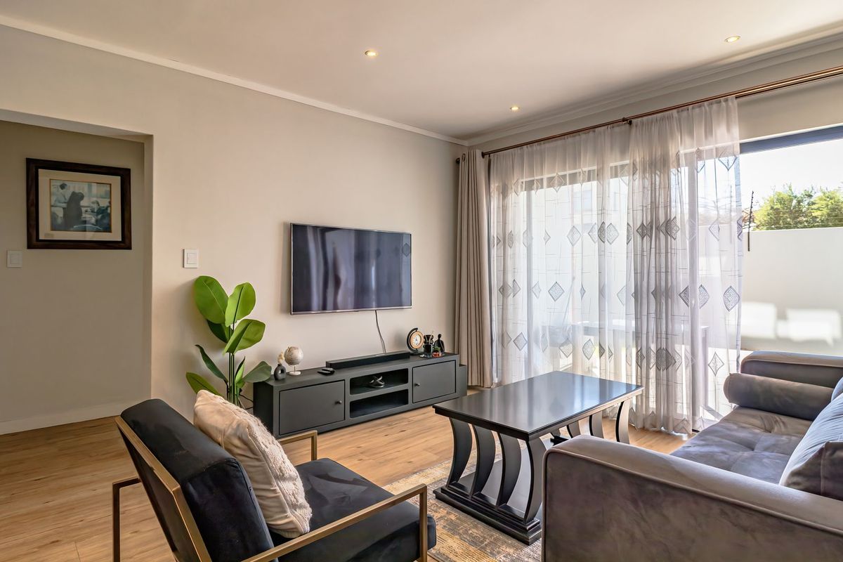 A well-maintained living room featuring laminate flooring, recessed lighting, and a large sliding glass door providing access to the outdoor area.
