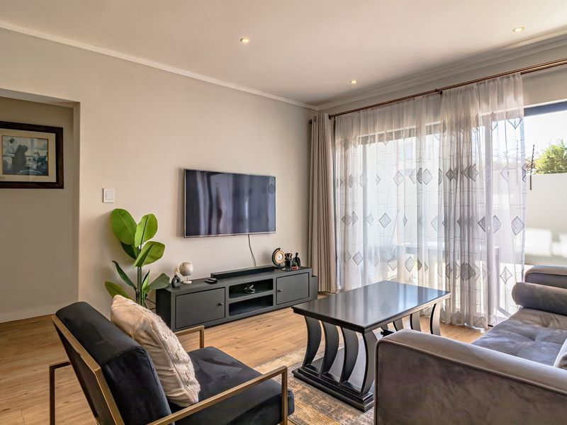 A well-maintained living room featuring laminate flooring, recessed lighting, and a large sliding glass door providing access to the outdoor area.
