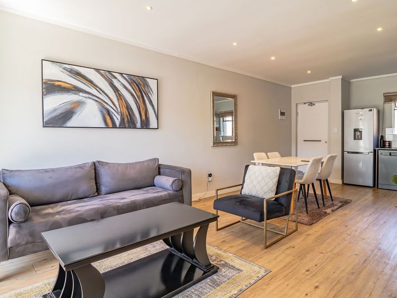 A well-maintained open-plan living and dining area featuring laminate flooring, recessed lighting, and a functional integrated kitchen space.