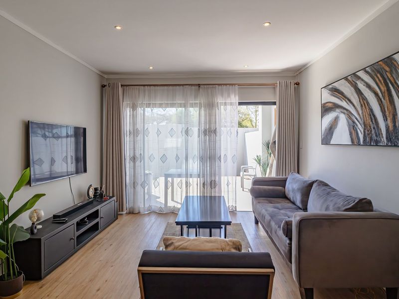 A well-maintained living room featuring laminate flooring, recessed lighting, and a large sliding glass door providing access to an outdoor patio area.