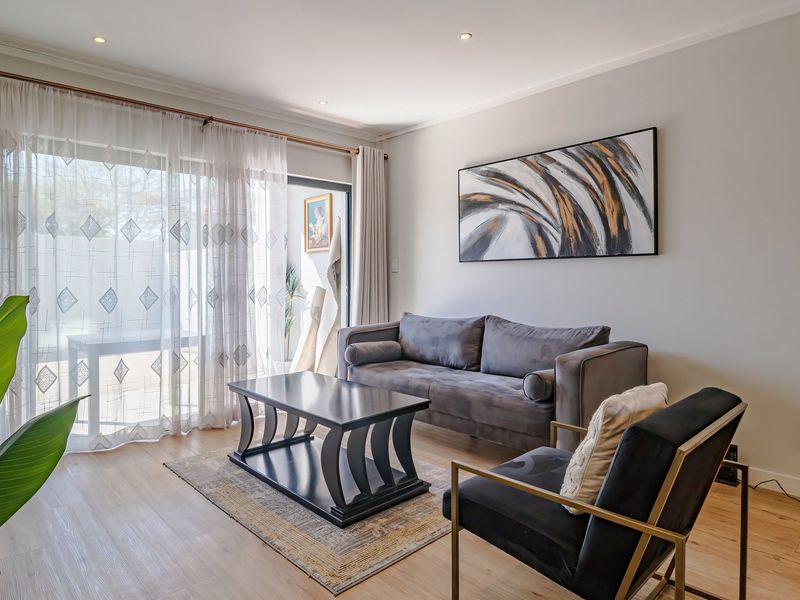 A bright and well-maintained living room featuring laminate flooring, recessed lighting, and a large sliding glass door providing access to the outdoor area.