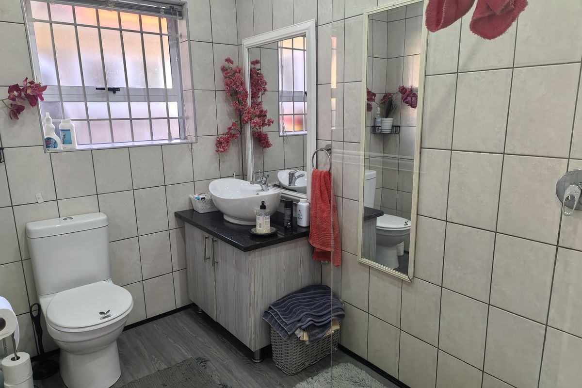 A functional bathroom featuring a vanity with a vessel sink, a toilet, and a shower enclosure with full-height wall tiling.