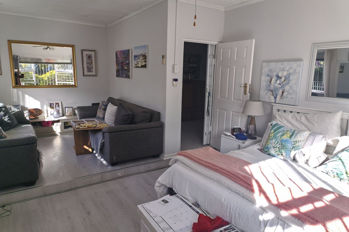 A bedroom featuring a raised platform area, light laminate flooring, and a panelled ceiling, offering a versatile layout with an adjoining space.