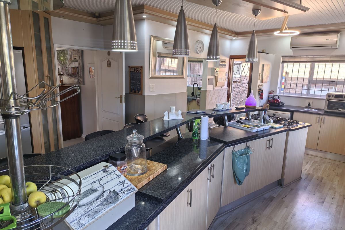 Spacious kitchen featuring granite countertops, extensive built-in cabinetry, a gas hob, and modern pendant lighting, offering a functional and well-lit cooking space.