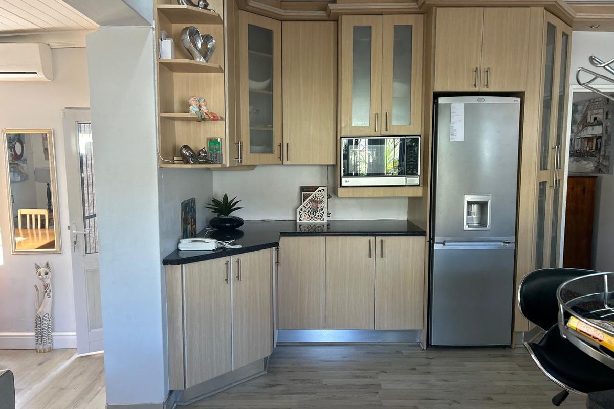 A functional kitchen featuring light wood-tone cabinetry, dark granite countertops, and integrated appliance housing, providing a clean and practical workspace.