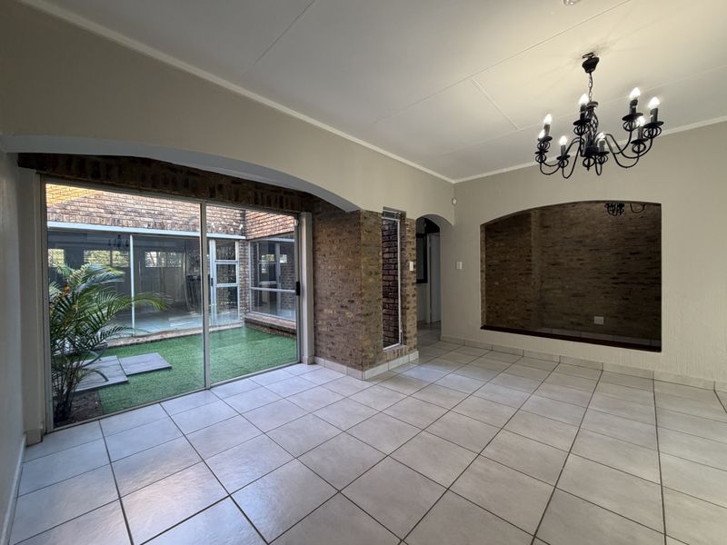 Spacious living area featuring tiled floors, exposed brick accents, a recessed wall niche, and large sliding doors opening to an internal courtyard.