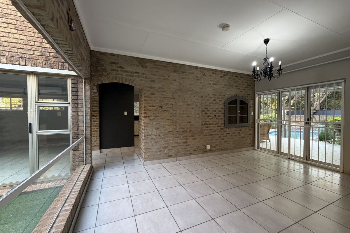 Spacious living area featuring exposed brick walls, tiled flooring, and large sliding glass doors providing access to the outdoor pool area.