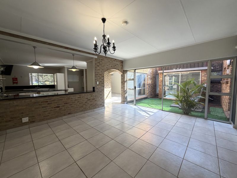 Spacious open-plan living area featuring tiled floors, exposed brick accents, a granite breakfast bar, and large sliding doors opening to a private courtyard.