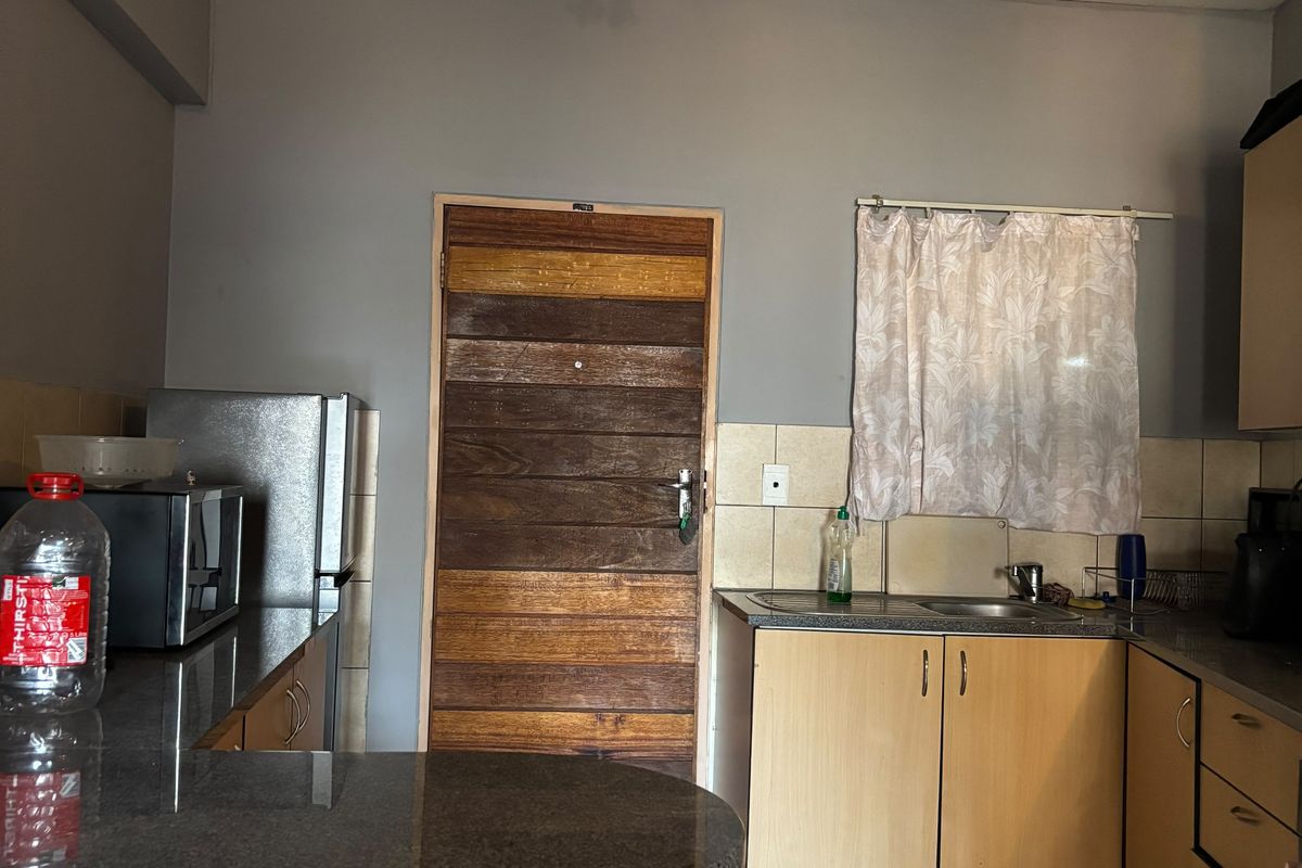Functional kitchen featuring granite countertops, laminate cabinetry, tiled backsplash, and tiled flooring, offering a practical layout for daily meal preparation.