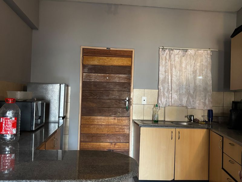 Functional kitchen featuring granite countertops, laminate cabinetry, tiled backsplash, and tiled flooring, offering a practical layout for daily meal preparation.