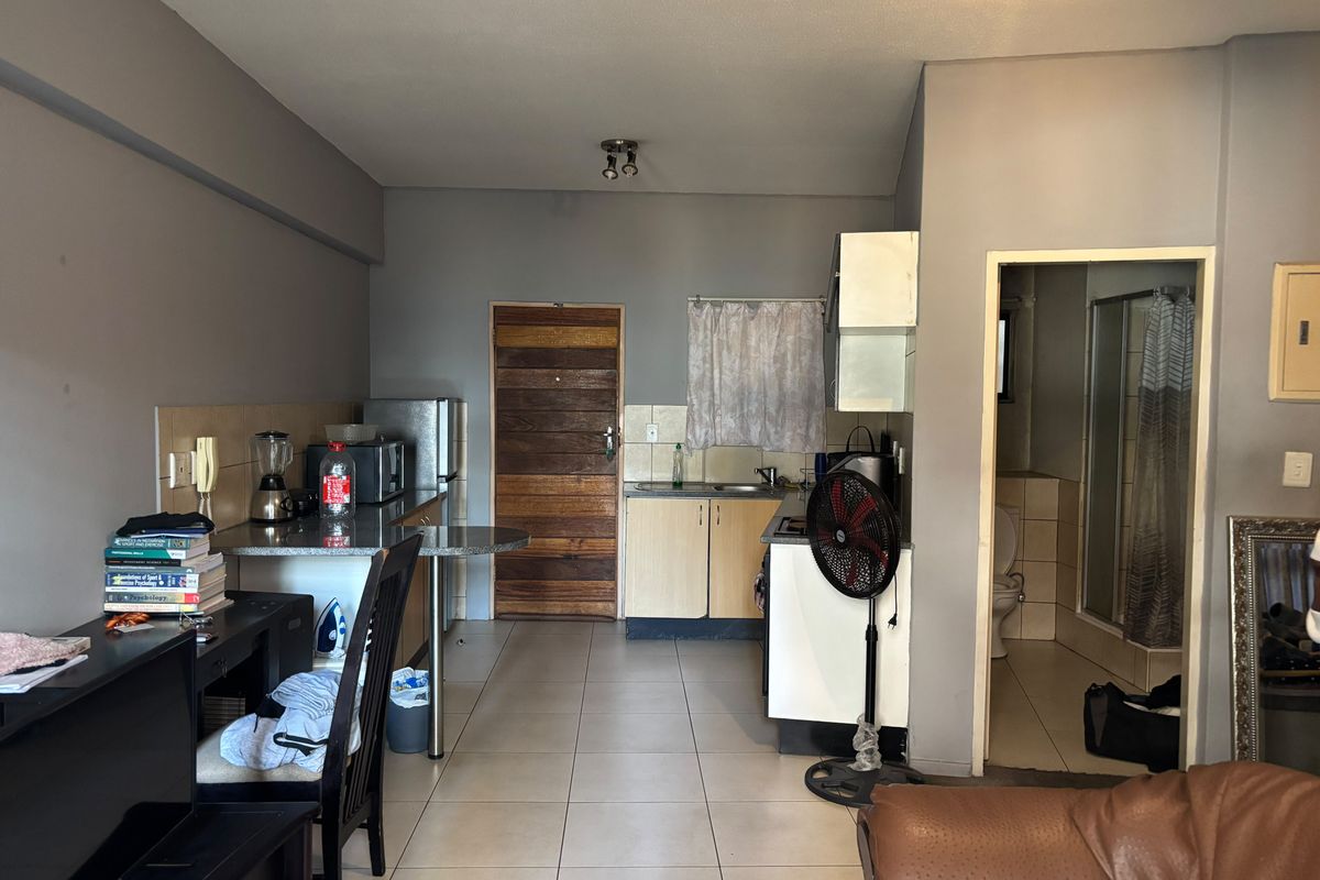 Open plan kitchen area with tiled flooring and direct access to the bathroom, featuring basic cabinetry and functional layout.