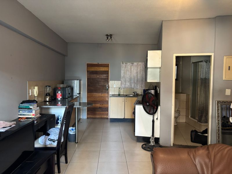 Open plan kitchen area with tiled flooring and direct access to the bathroom, featuring basic cabinetry and functional layout.