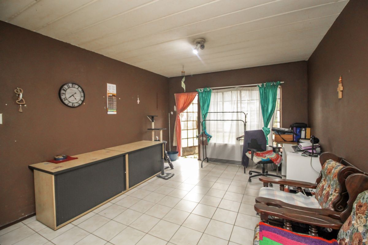 A living room featuring tiled flooring, dark brown walls, and a sliding glass door providing access to the exterior.