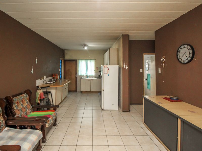 Open-plan living and kitchen area featuring tiled flooring, basic cabinetry, and a functional layout in need of cosmetic updates.