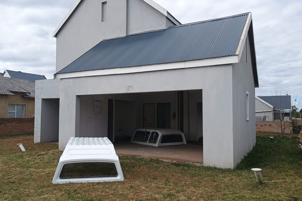 Rear view of a double-story townhouse featuring a corrugated metal roof, plastered exterior walls, and an open-plan ground floor area.