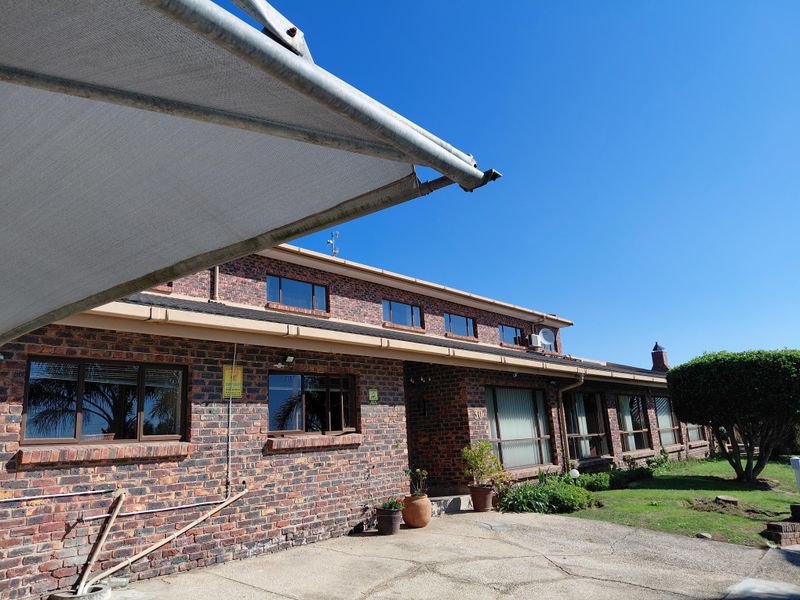 Front elevation of a single-story face brick house featuring aluminium windows, a concrete driveway, and an installed shade sail.