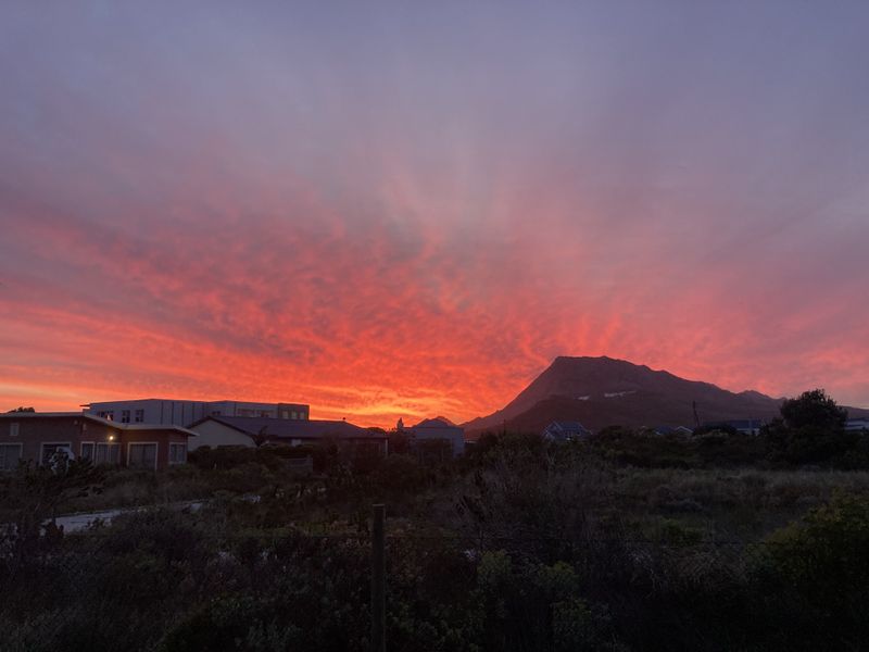 A scenic sunset view overlooking the surrounding landscape, mountain range, and residential neighborhood.