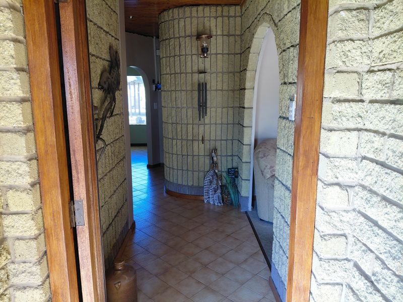 A hallway featuring distinctive textured brick walls, arched entryways, tiled flooring, and a timber ceiling, providing a unique architectural character.