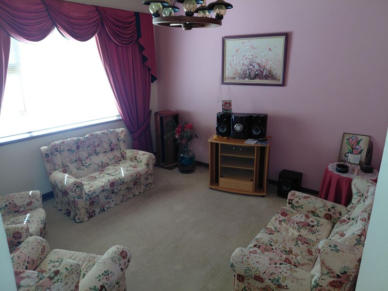 A traditional living room featuring carpeted flooring, a large window with heavy drapery, and a central ceiling light fixture.