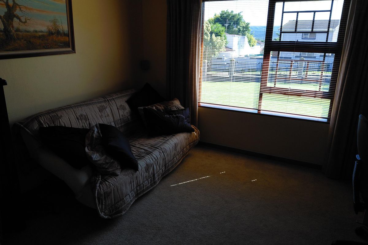 A bedroom featuring carpeted flooring and a large window with venetian blinds, offering natural light and a view of the exterior.