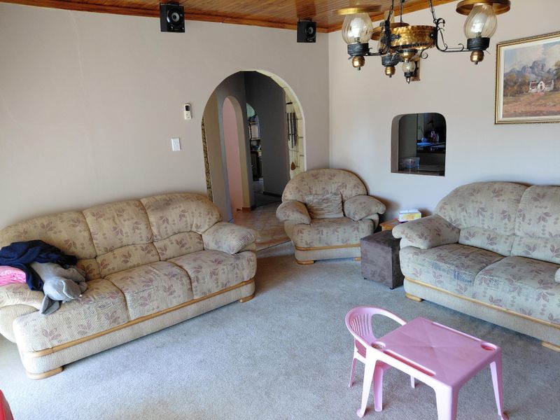 A living room featuring a timber ceiling, an arched doorway leading to adjacent spaces, and a serving hatch connecting to the kitchen area.